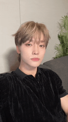 a young man is sitting on a couch taking a selfie with his phone .