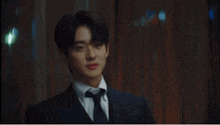 a man in a suit and tie is standing in a room .