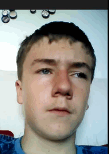 a young man with a red nose and a blue shirt looks at the camera