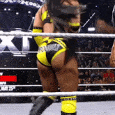 a woman is standing in a wrestling ring wearing a pair of yellow shorts with the word honey on them .