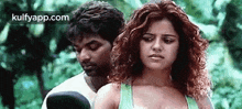 a man and a woman are standing next to each other . the woman is wearing a green tank top .