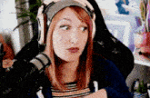 a woman wearing headphones and a beanie is sitting in front of a microphone .