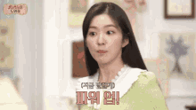a woman in a green sweater and white collar is standing in a living room .
