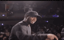 a man wearing a baseball cap is giving a thumbs up sign in front of a crowd .