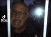 a man with glasses and a beard is behind a fence with a tik tok watermark