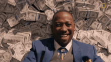 a man in a suit and tie is smiling while laying in a pile of money
