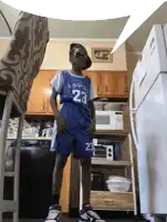 a boy wearing a jersey that says cb sport 23 stands in a kitchen