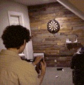 a man is taking a picture of a dart board on a wooden wall