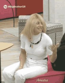 a woman is sitting on a pink chair that says amalia on it