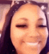 a close up of a woman 's face with her eyes closed and a smile .