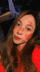 a woman with kisses on her face is wearing a red hoodie .