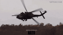 a benjosak nato helicopter flies over a forest