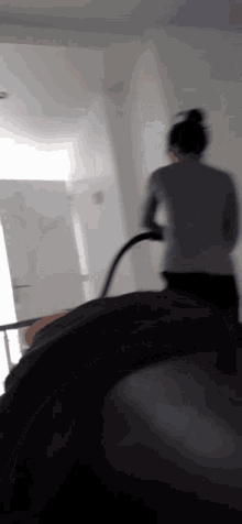 a woman is standing in a room with a vacuum cleaner