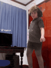 a young boy is dancing in front of a computer and a sign that says viggle.ai