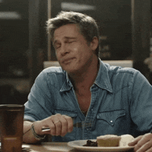 a man in a denim shirt is sitting at a table with a plate of food and the words what do you do below him