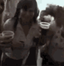 a woman is holding a cup of beer in her hand while standing next to another woman .