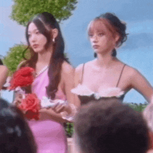 two women in pink dresses are standing next to each other in a crowd .