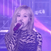 a woman in a zebra print shirt is singing into a microphone on a stage .