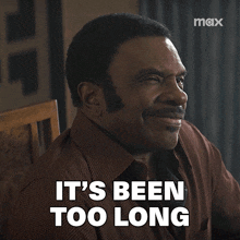 a man sitting in a chair with the words it 's been too long