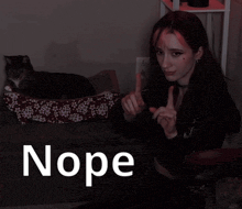 a woman is sitting in front of a cat and the word nope is on the bottom