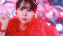 a woman in a red dress with a red headband looks at the camera