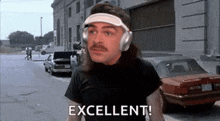 a man wearing headphones and a visor is standing on a street and says excellent .