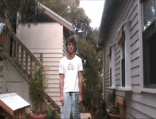 a man standing in front of a house wearing a shirt that says ' jesus '