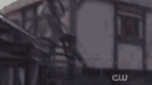 a man is swinging a sword in front of a building with the cw logo