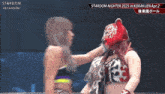 two women are wrestling in a ring and one of them has a mask on her face .