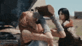 a woman is drinking water from a bottle while standing next to a car with the hood up .