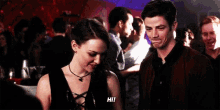 a man and a woman are standing next to each other in a crowded room at a party .