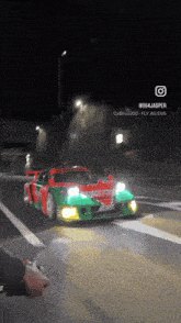 a green and red sports car is driving down a street