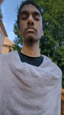 a man is wrapped in a blanket and looking at the camera .