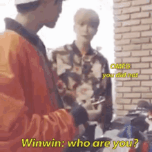 two men are standing next to each other in front of a brick wall and one of them is asking the other who are you .