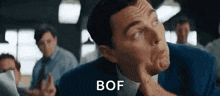 a man in a suit and tie is making a funny face in front of a group of men .