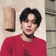 a young man in a red shirt is standing in front of a building .