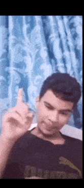 a young man in a black puma shirt is making a funny face