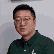 a man wearing glasses and a green shirt with a white letter l on it