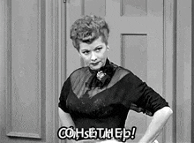 a woman in a black and white photo is standing in front of a door and talking .