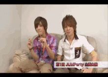 two young men are sitting on a couch and one of them is wearing a white shirt that says jumpparty