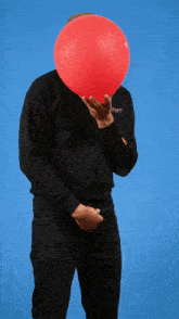 a man holding a red balloon in front of his face wearing a black sweatshirt that says ' balenciaga ' on it