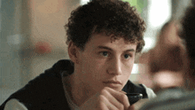 a young man with curly hair is looking at another man