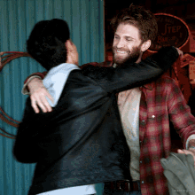 a man in a plaid shirt is hugging another man