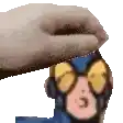 a hand is putting a cartoon character 's head on a white surface .