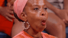 a woman wearing hoop earrings and a headband makes a funny face