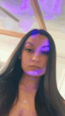 a woman with long dark hair is standing in front of a purple light .