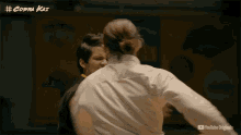 a man and a woman are fighting in front of a poster that says # cobra kai