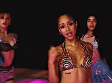 a woman in a bikini top is standing next to another woman in a bikini top .