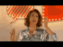a woman is making a speech bubble with her hands in front of a red sign .