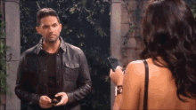 a man and a woman are standing next to each other and the woman is holding a cell phone .